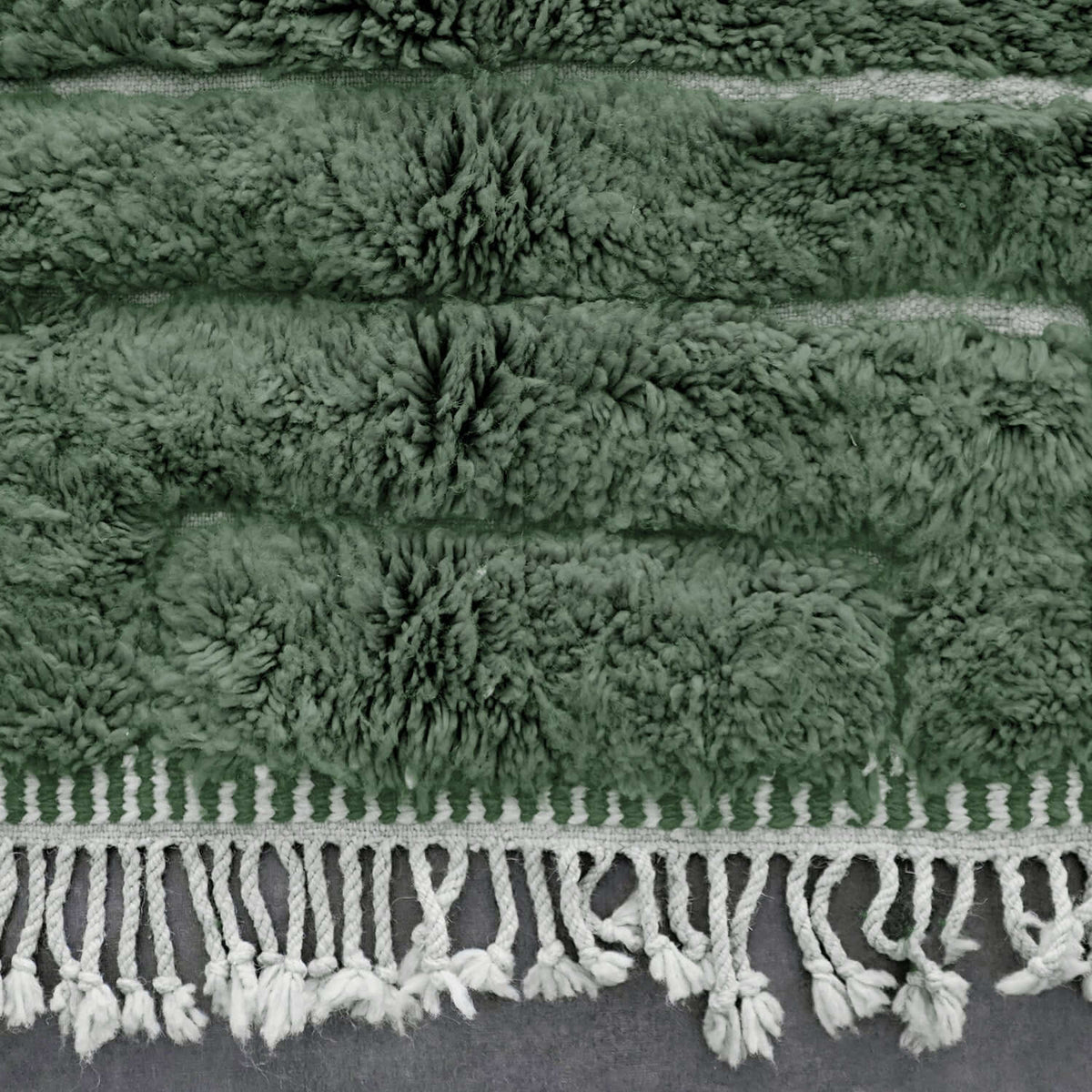 VerdeBer rug border with wool fringe and subtle tribal motifs in green tones