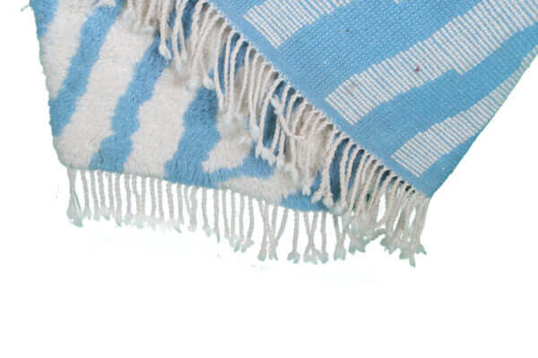 Custom Moroccan rug runner with blue and white wavy stripe Berber Moroccan rug design, handwoven from wool, featuring fringed edges for a chic Moroccan rug area.