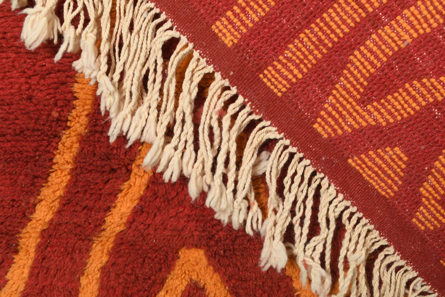 Custom Moroccan rug runner with red base and orange zigzag Berber Moroccan rug design, handwoven from wool, featuring fringed edges for a stylish Moroccan rug area.