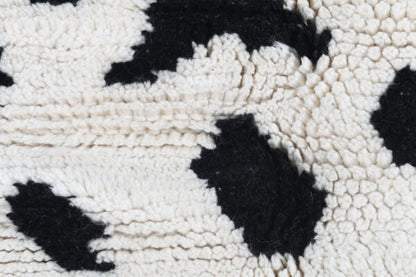 Custom Moroccan rug runner with white base and scattered black abstract Berber Moroccan rug design, handwoven from wool, featuring fringed edges for a unique Moroccan rug area.