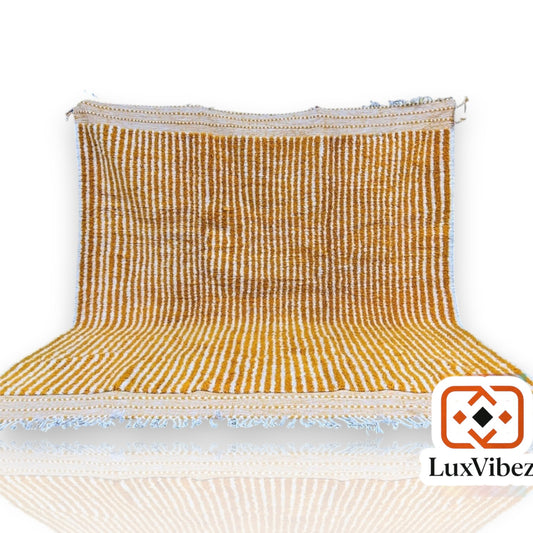 Colorful Beni Ourain rug with checkered white, black, and orange pattern, fringed edges, displayed with a vase on a wooden floor.