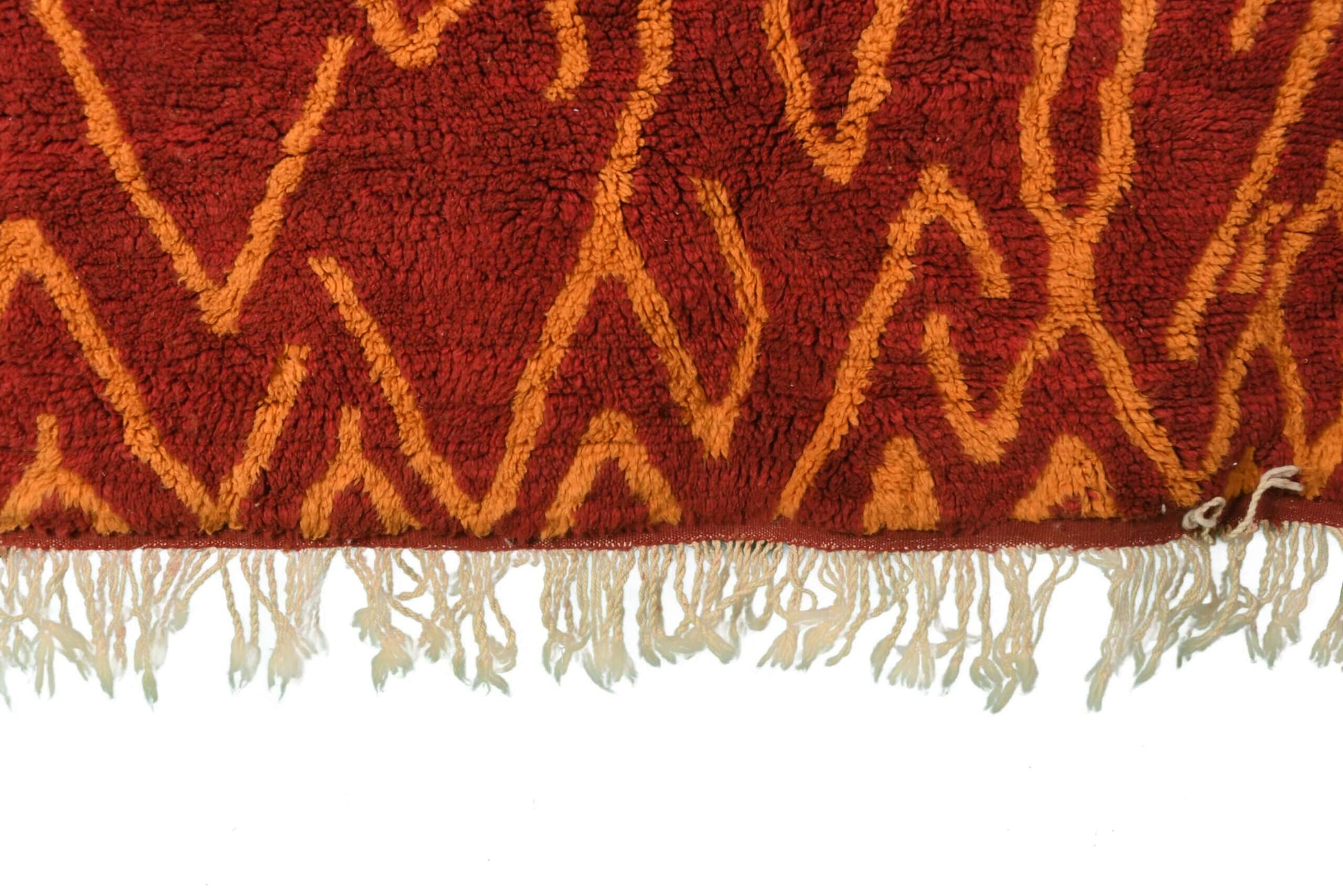 Custom Moroccan rug runner with red base and orange zigzag Berber Moroccan rug design, handwoven from wool, featuring fringed edges for a stylish Moroccan rug area.
